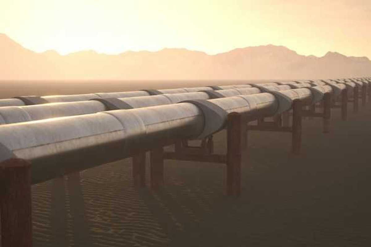 A row of pipelines stretching across a dry environment with mountains in the background