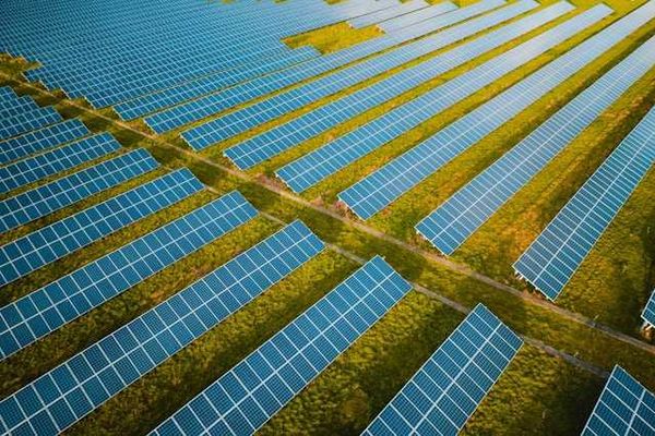 A row of solar panels stretching across a green landscape
