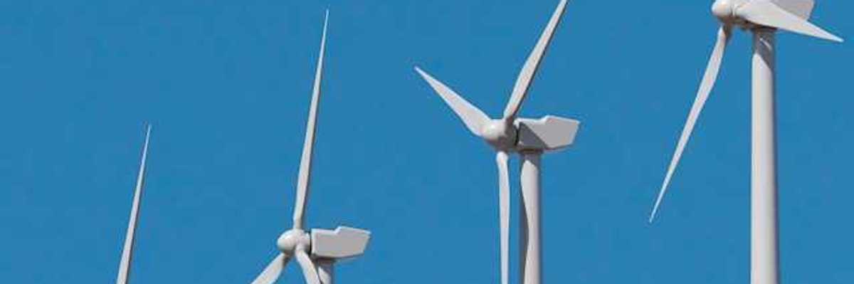 A row of wind turbines against a blue sky