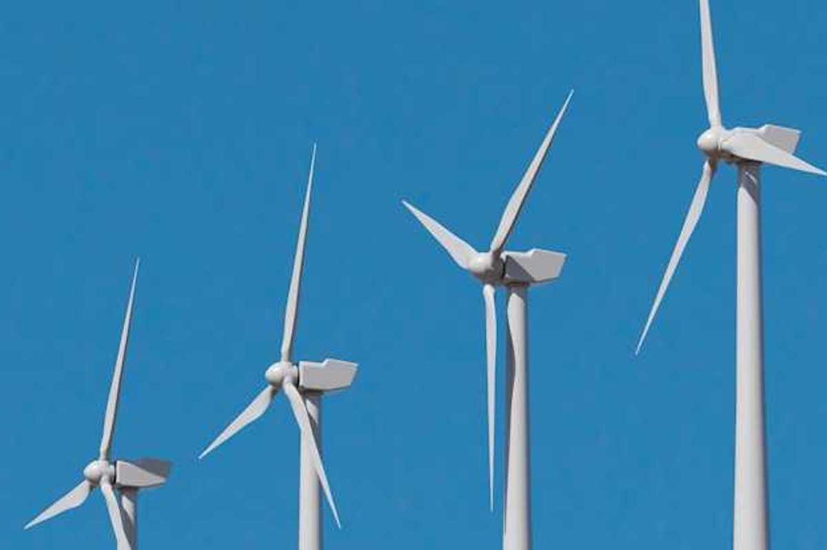A row of wind turbines against a blue sky
