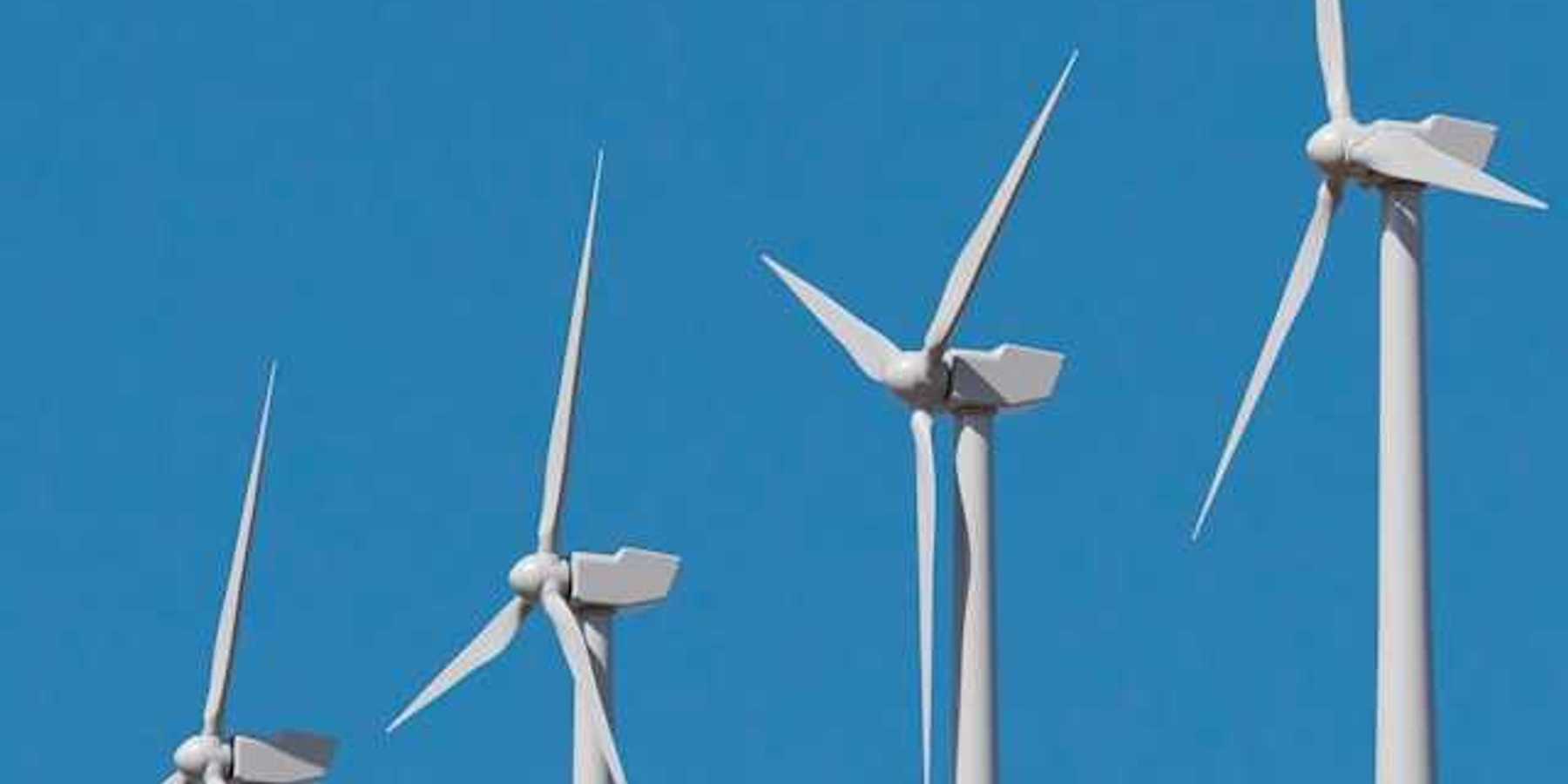 A row of wind turbines against a blue sky