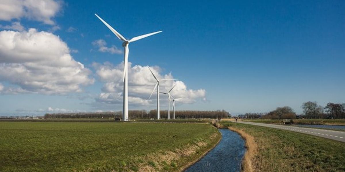 A row of wind turbines alongside a canal.