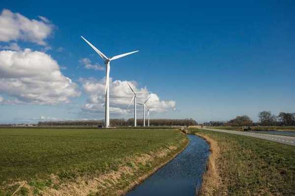 A row of wind turbines alongside a field