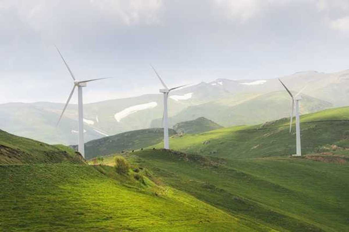 A row of wind turbines on green hills