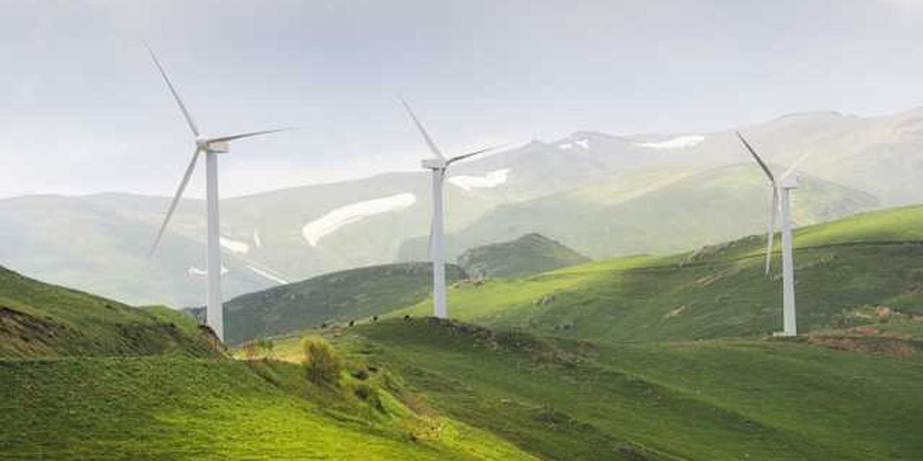 A row of wind turbines on green hills