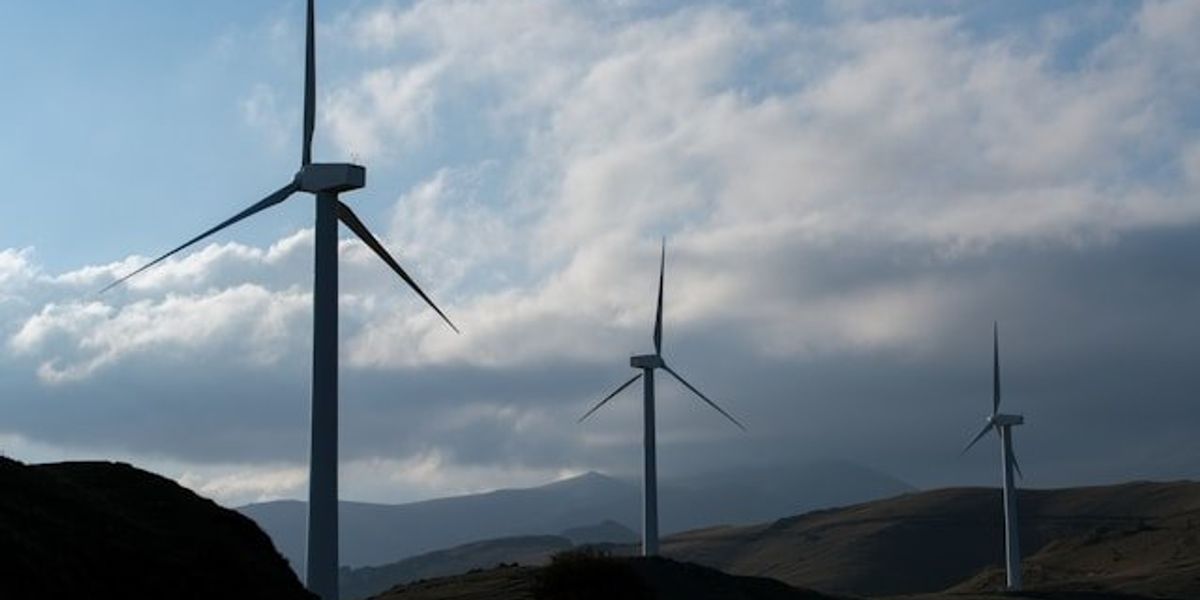 A row of wind turbines stretching across the hills.