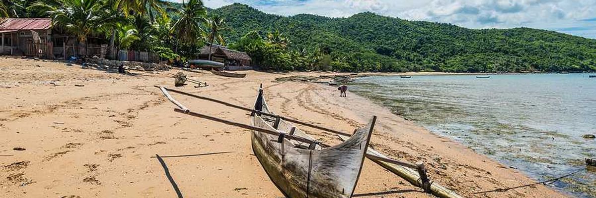 A rustic boat sitting on a beach beside the ocean
