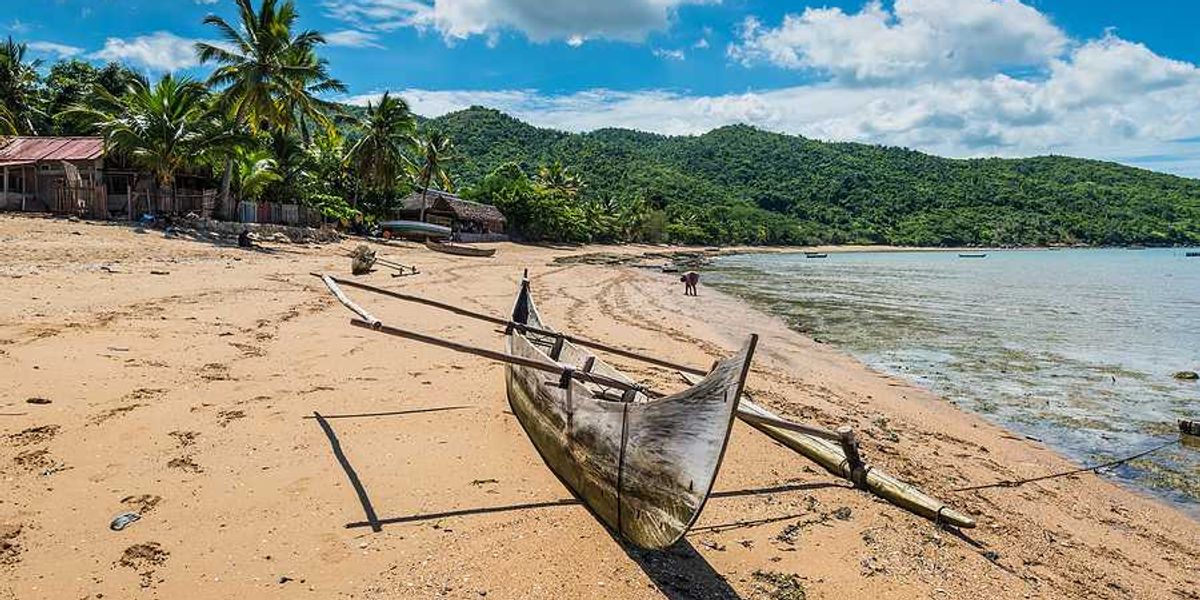 A rustic boat sitting on a beach beside the ocean