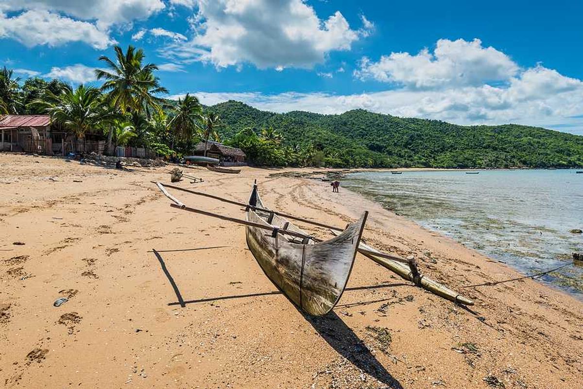 A rustic boat sitting on a beach beside the ocean