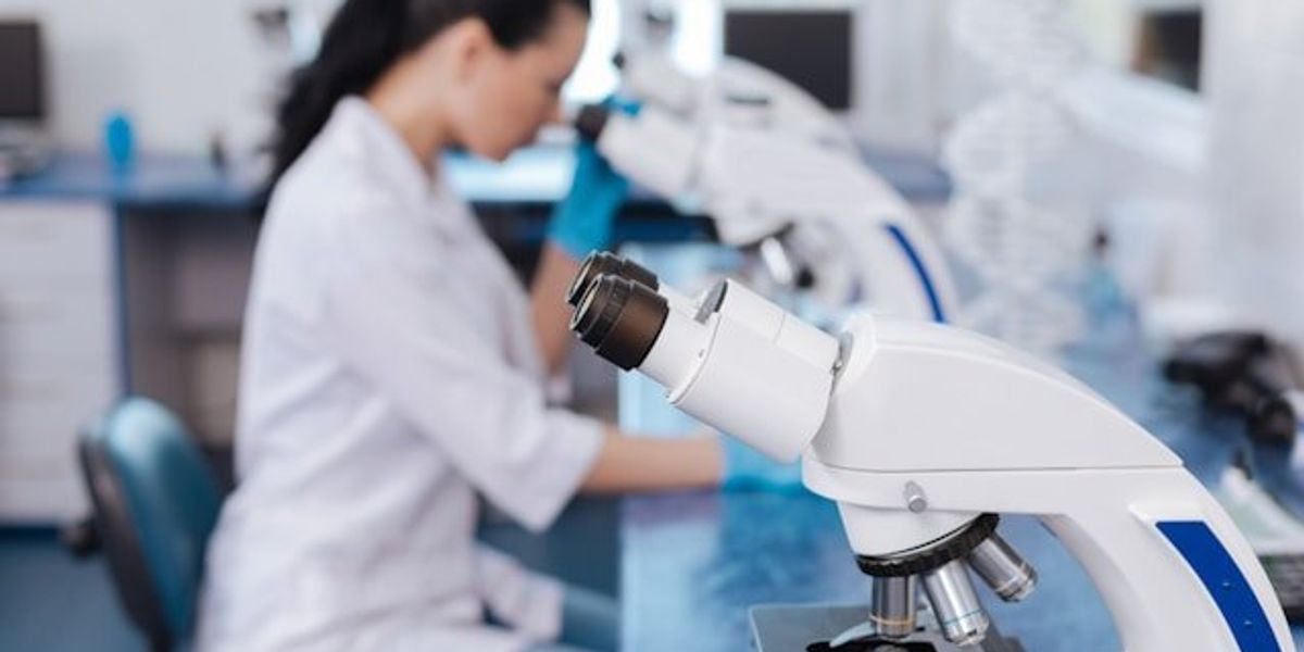 A scientist sitting in a lab at a microscope.