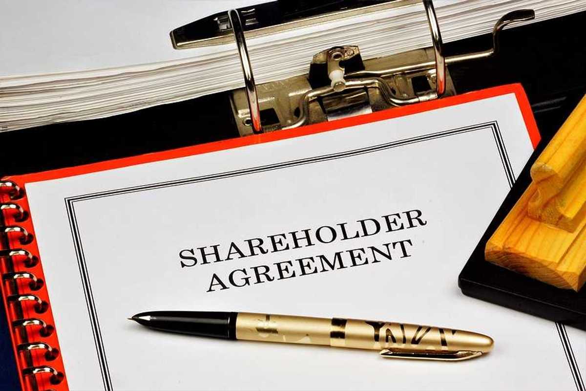 A shareholder agreement with a gold pen on top of it