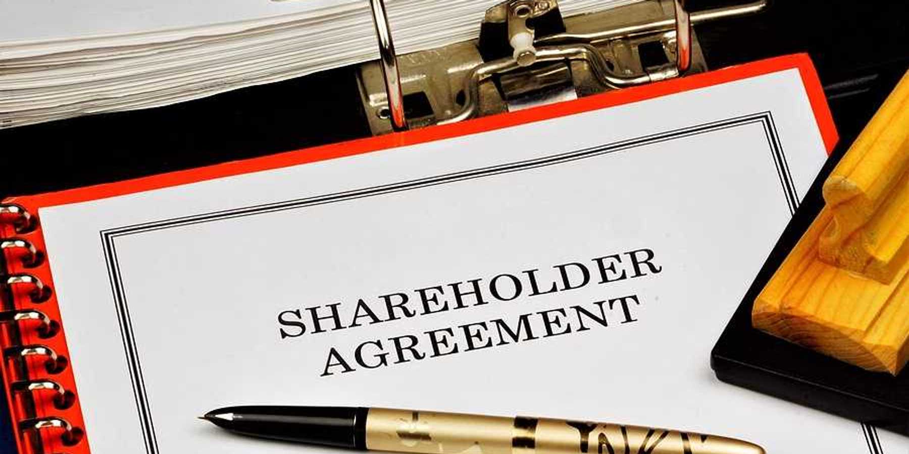 A shareholder agreement with a gold pen on top of it