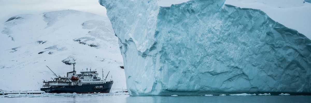 A ship sailing past a large iceberg