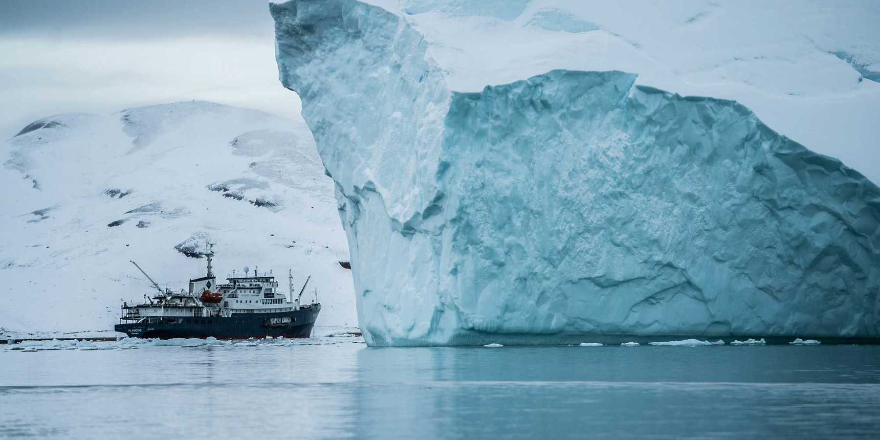 A ship sailing past a large iceberg