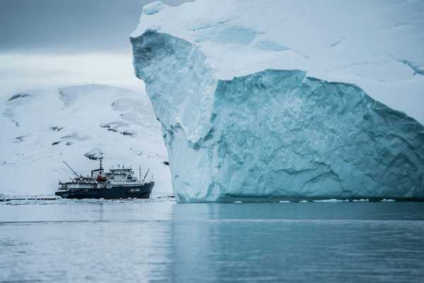 A ship sailing past a large iceberg