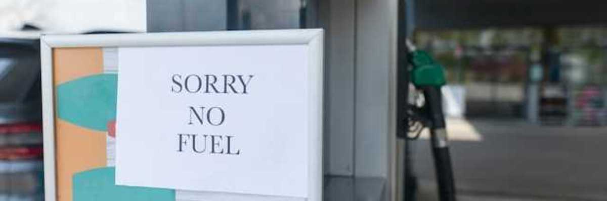 A sign that says 'sorry no fuel' next to a gas station pump