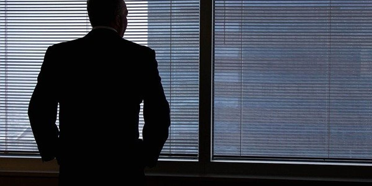 A silhouette of a business man against an office window