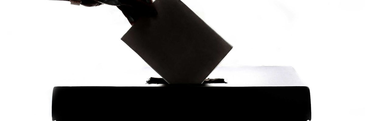 A silhouette of a person casting a vote into a box