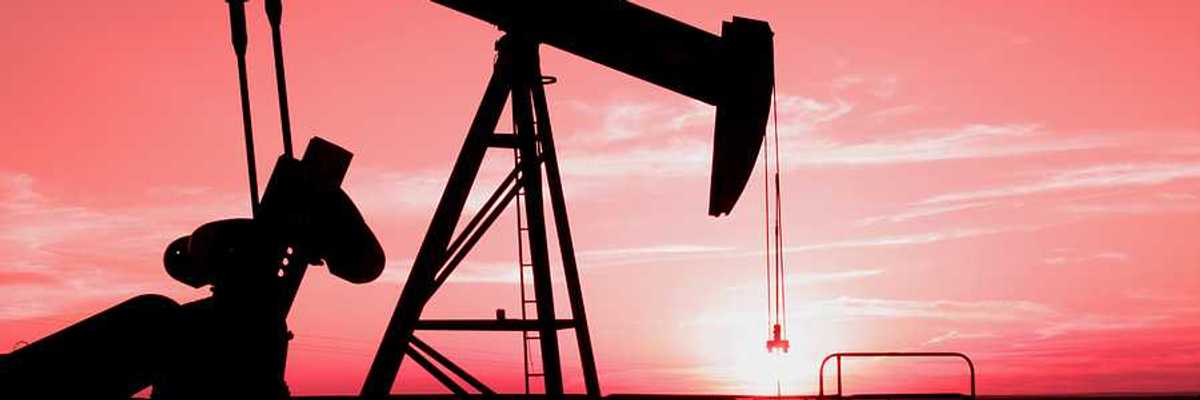 A silhouette of an oil pump jack with the sunset in the distance