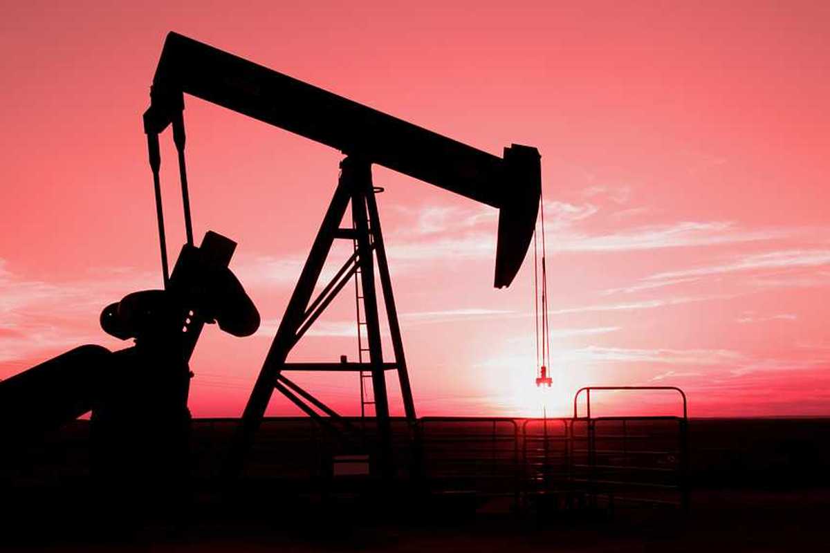 A silhouette of an oil pump jack with the sunset in the distance