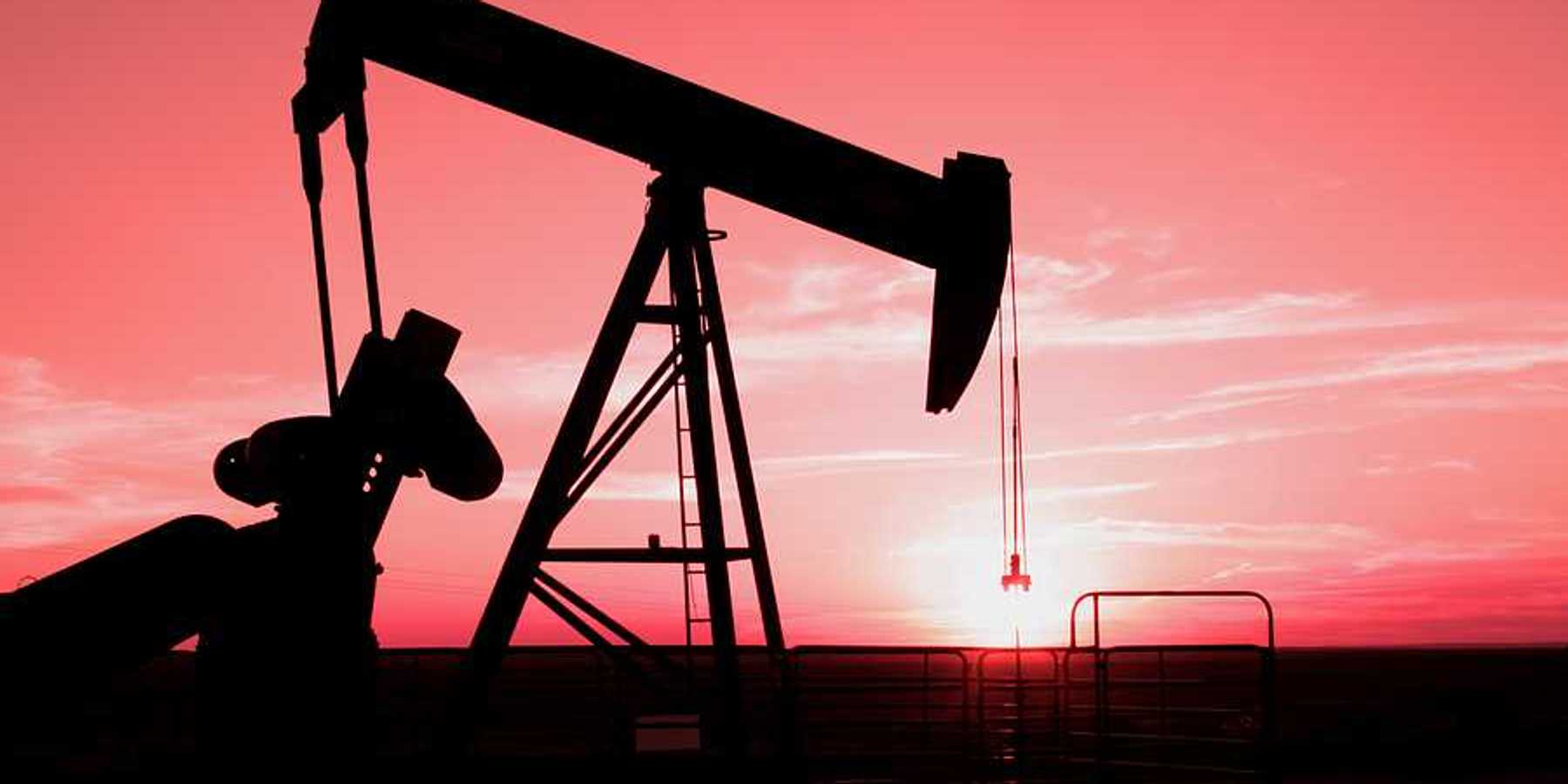 A silhouette of an oil pump jack with the sunset in the distance