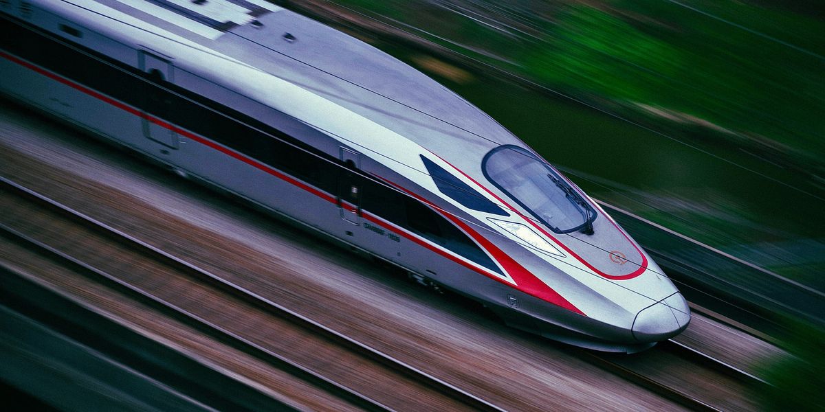 a silver and red train traveling down train tracks.