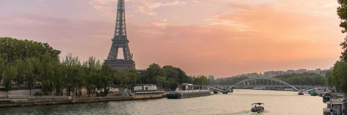 A single boat traveling the river Seine with the Eiffel Tower behind