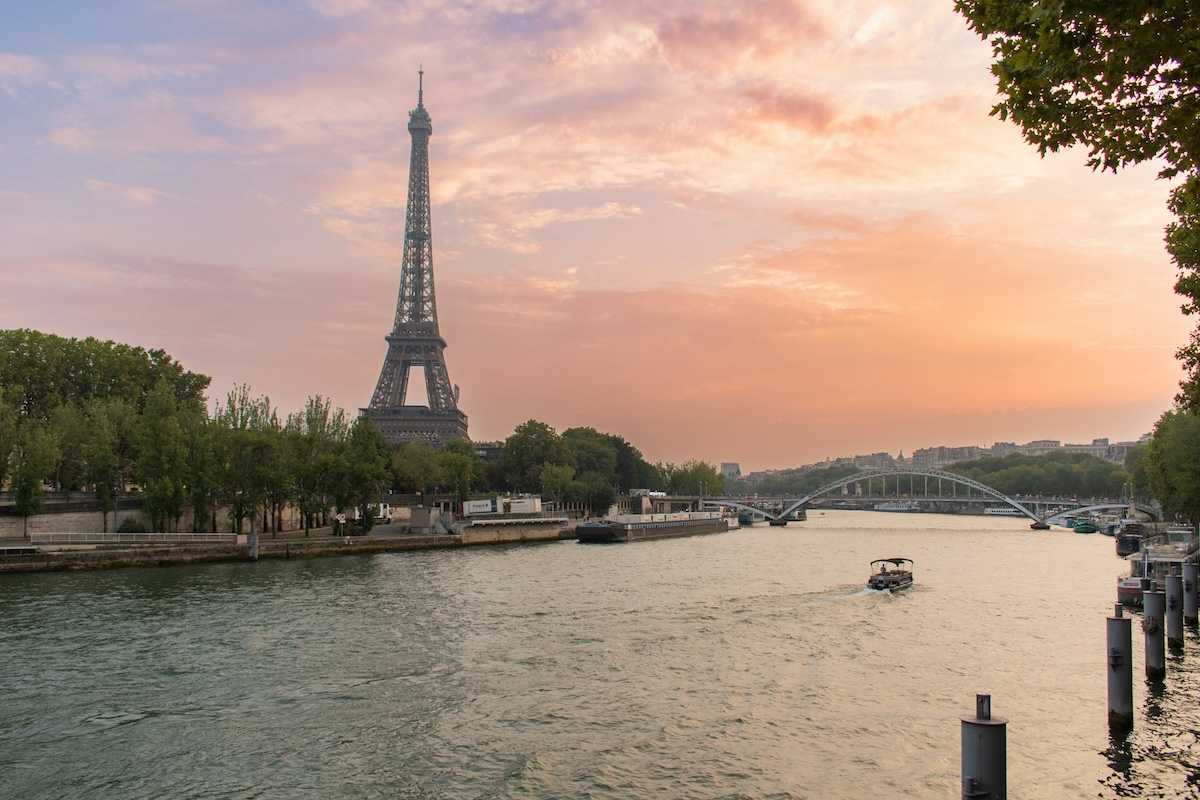 A single boat traveling the river Seine with the Eiffel Tower behind