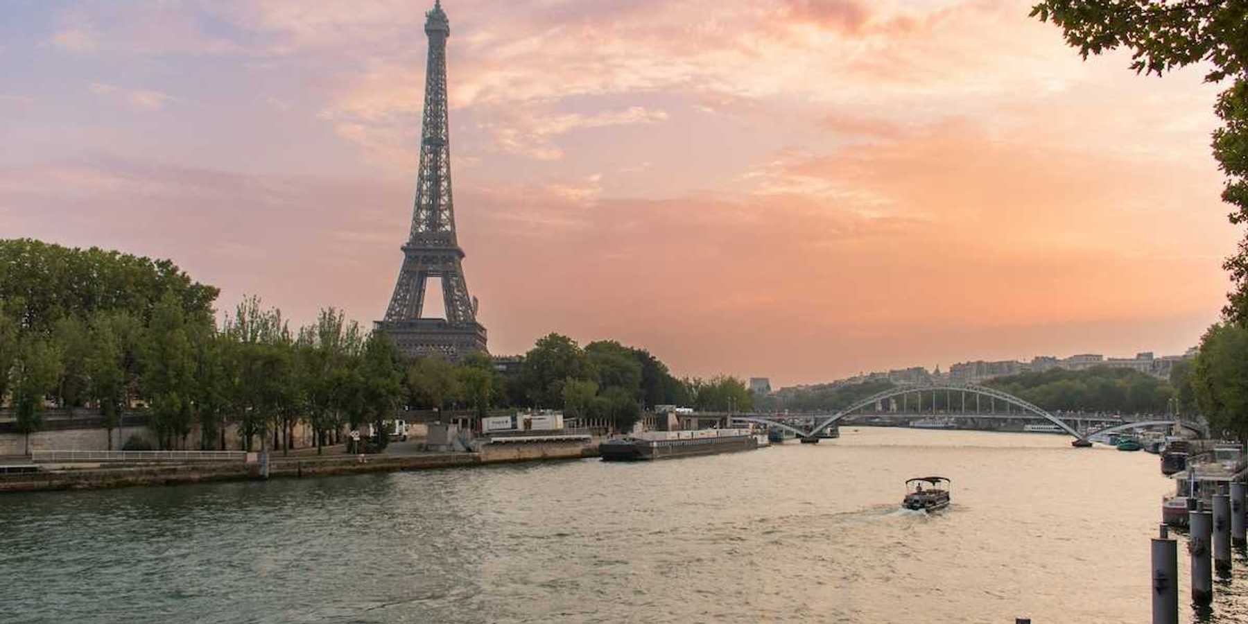 A single boat traveling the river Seine with the Eiffel Tower behind