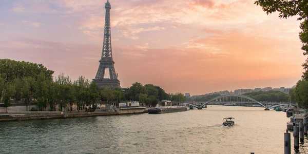 A single boat traveling the river Seine with the Eiffel Tower behind
