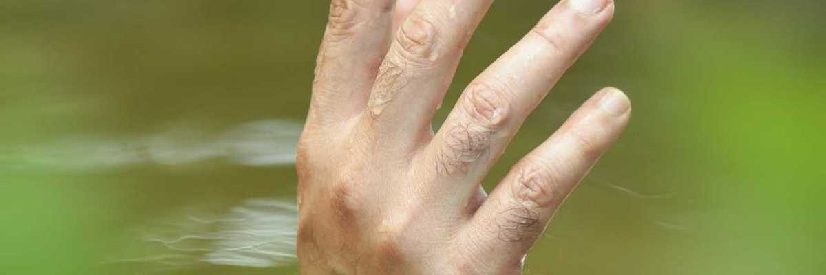 A single hand poking up out of floodwaters