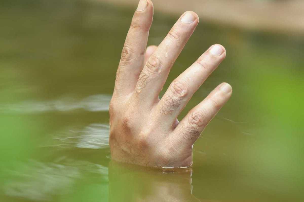 A single hand poking up out of floodwaters