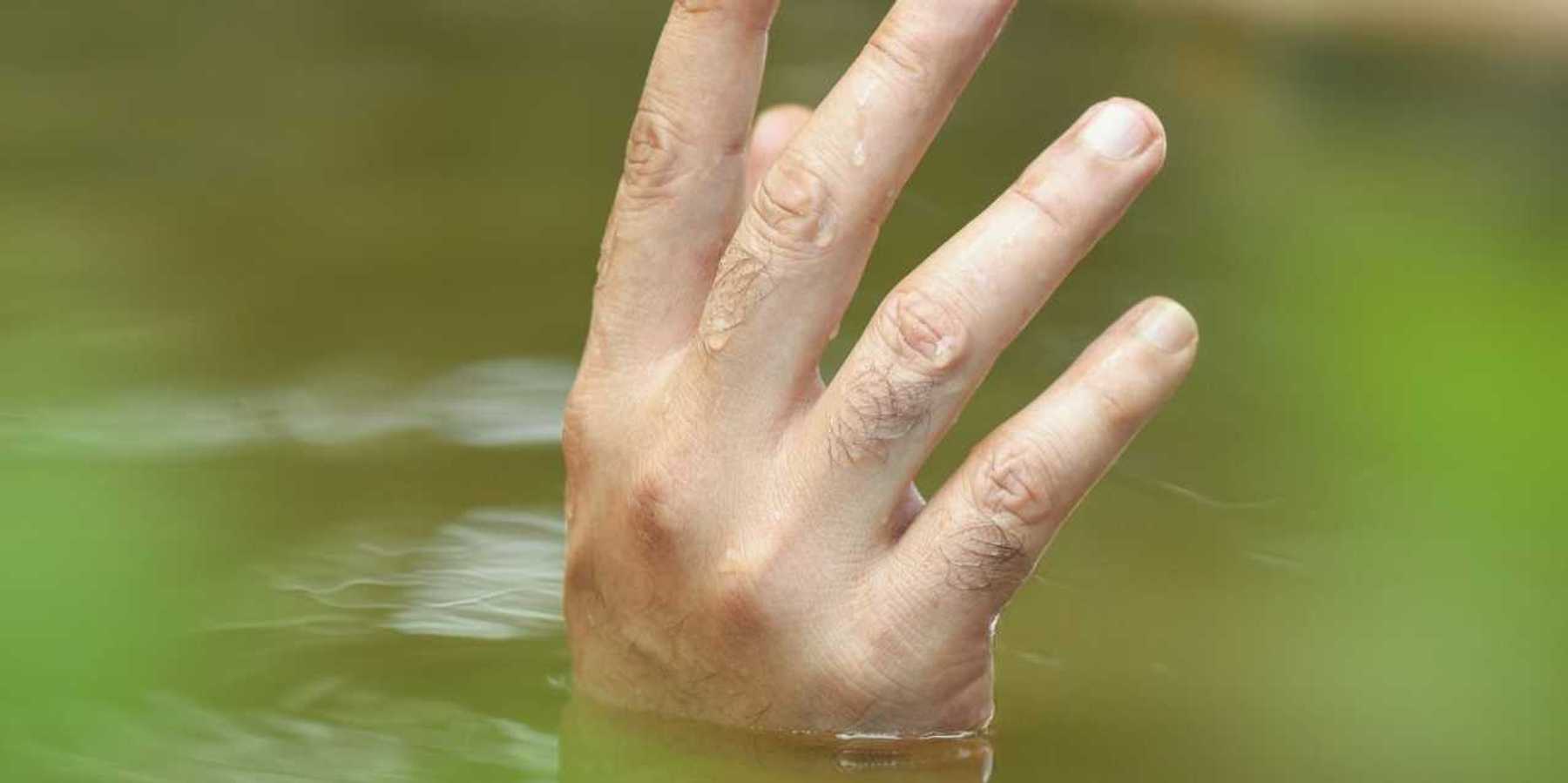 A single hand poking up out of floodwaters