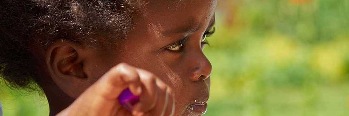 A small black child eating with a spoon