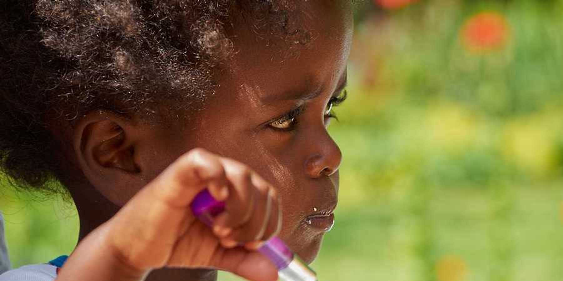A small black child eating with a spoon