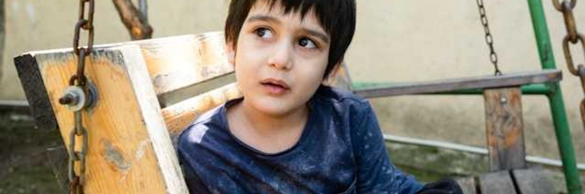 A small child sitting in a wooden swing in Afghanistan