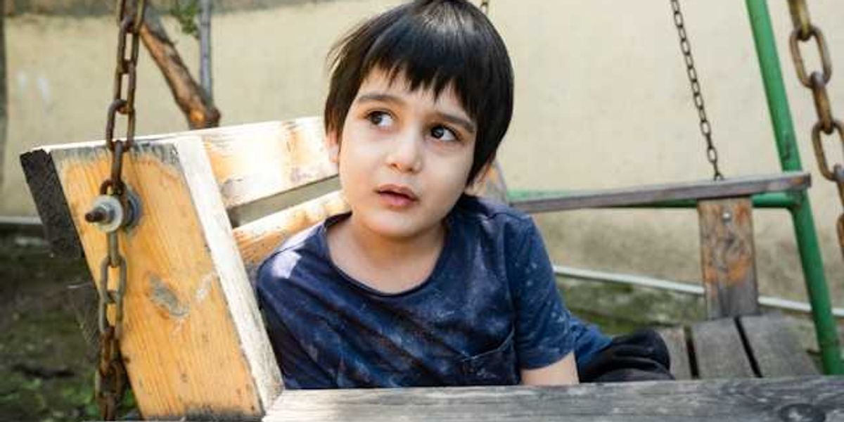A small child sitting in a wooden swing in Afghanistan