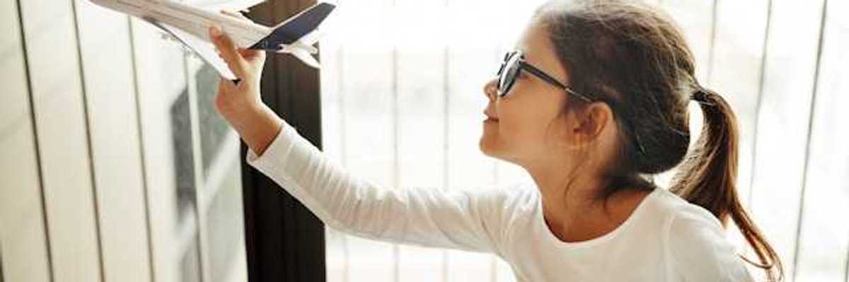 A small girl holding a model of an airplane