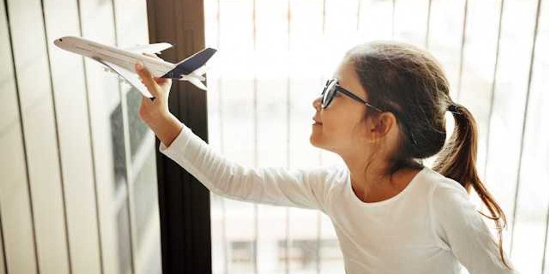A small girl holding a model of an airplane