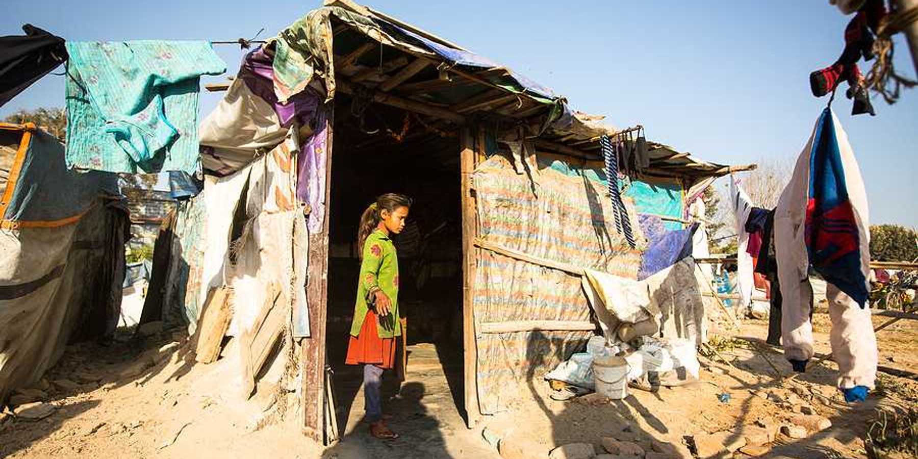 A small girl standing in the doorway of a hut