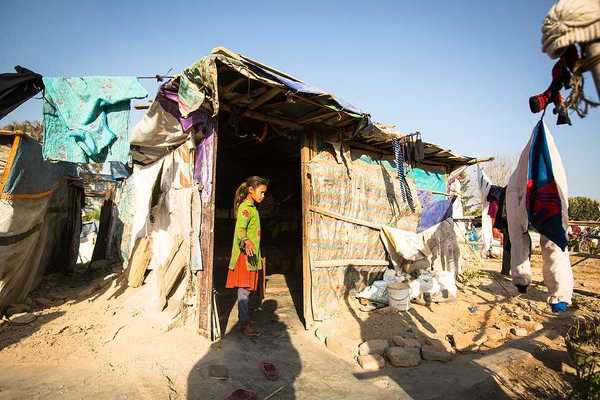 A small girl standing in the doorway of a hut