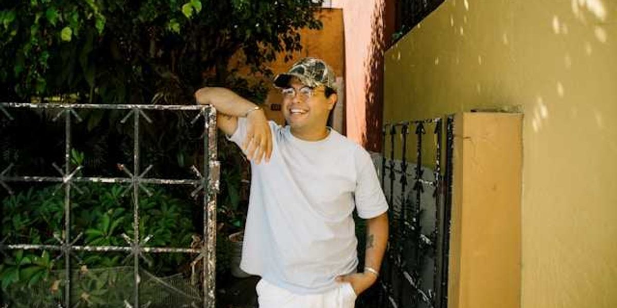 A smiling latino man standing next to a metal gate
