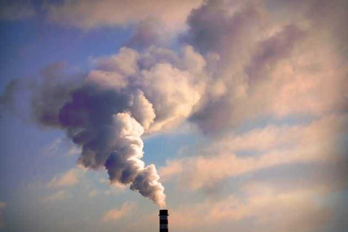A smoke stack with smoke billowing out into the clouds