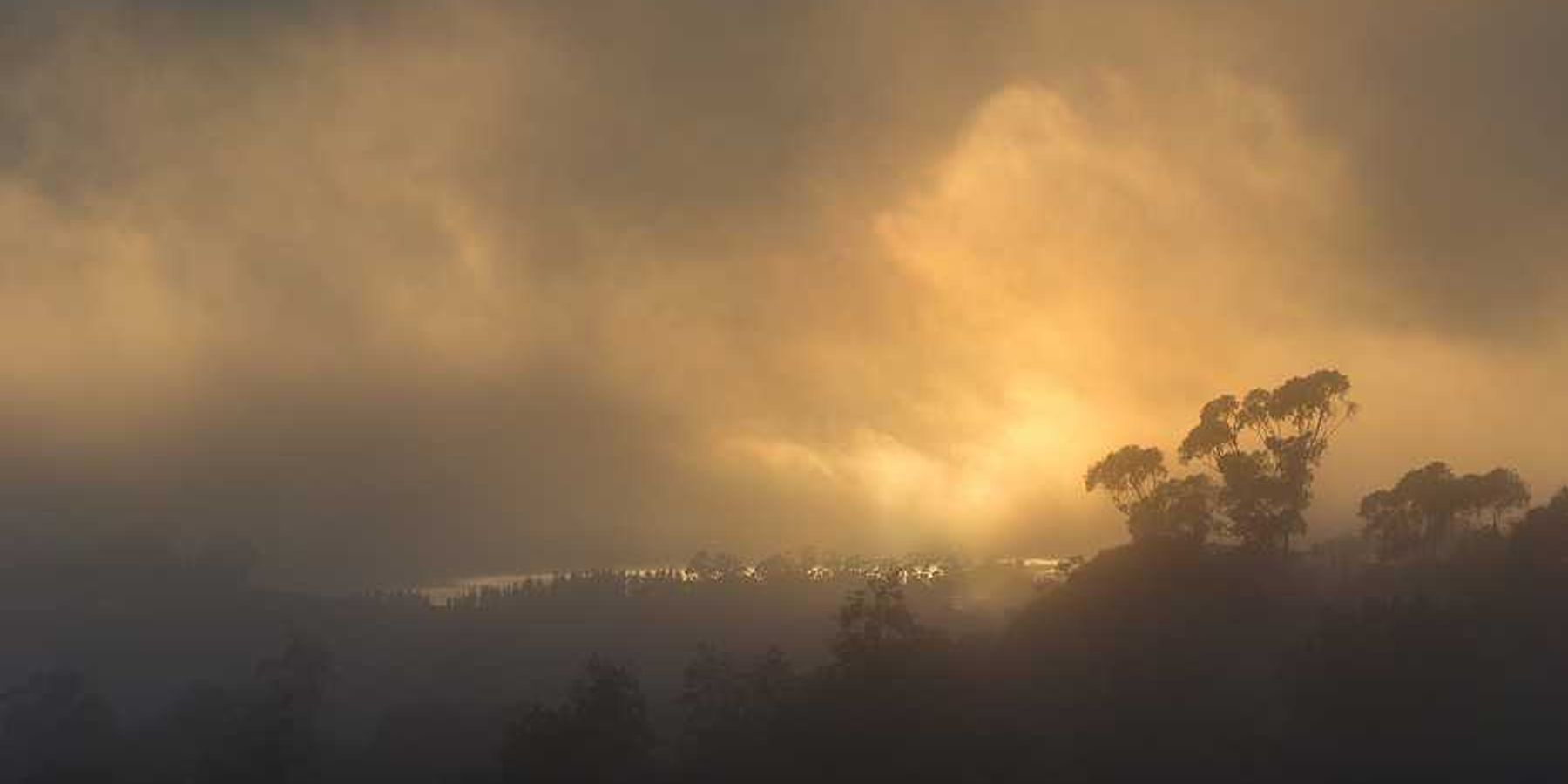 A smoky landscape with the sun in the background