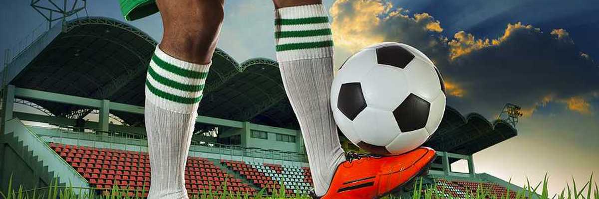 A soccer player balancing a soccer ball on the top of his foot