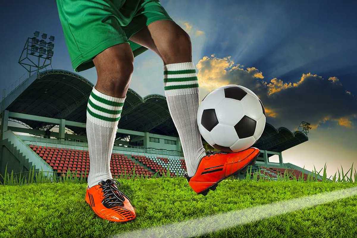 A soccer player balancing a soccer ball on the top of his foot