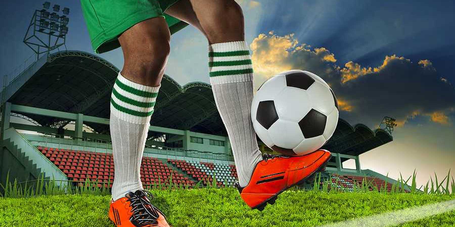 A soccer player balancing a soccer ball on the top of his foot