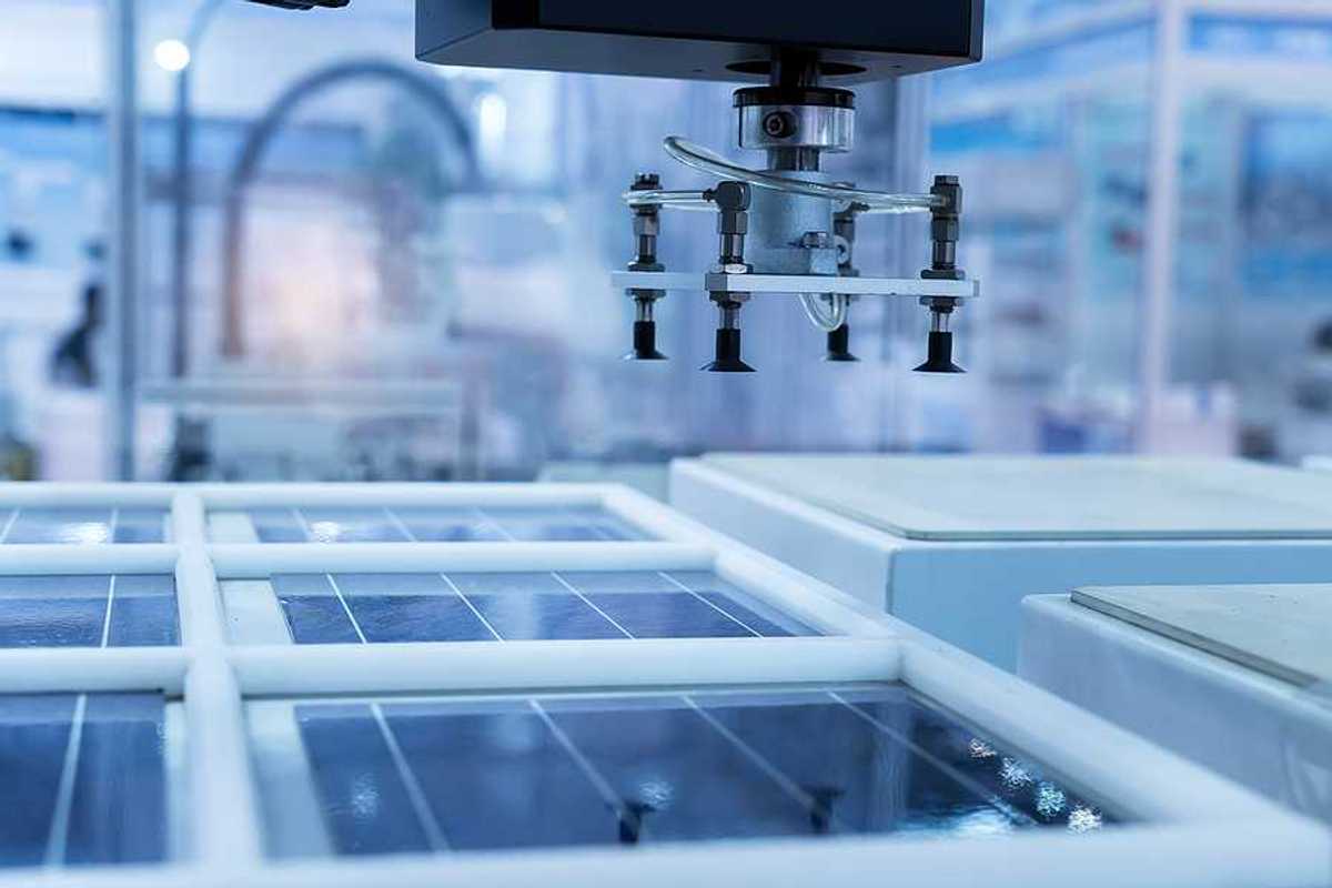 A solar panel in a manufacturing plant with a robotic arm hovering above it
