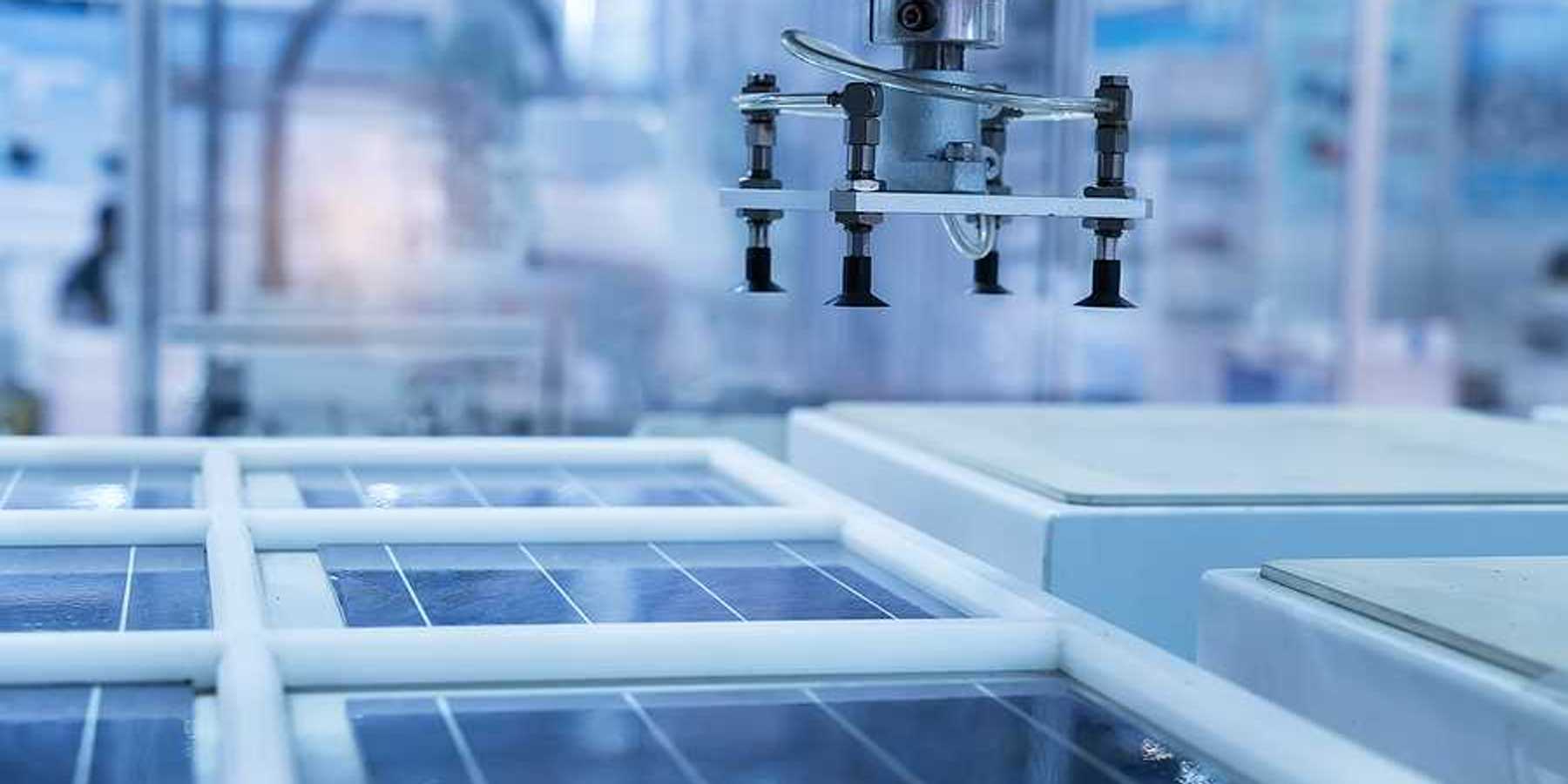 A solar panel in a manufacturing plant with a robotic arm hovering above it