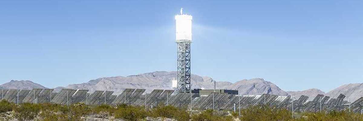 A solar tower above a desert landscape with solar panels
